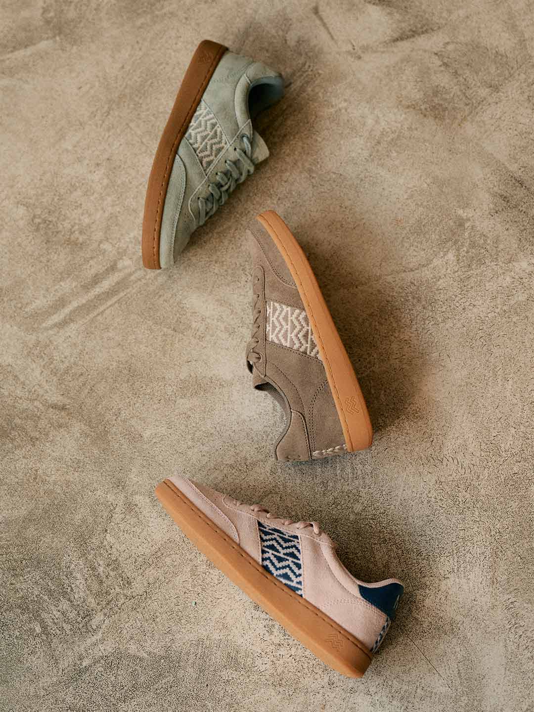 Trois sneakers en suède avec motifs ethniques sur fond beige.