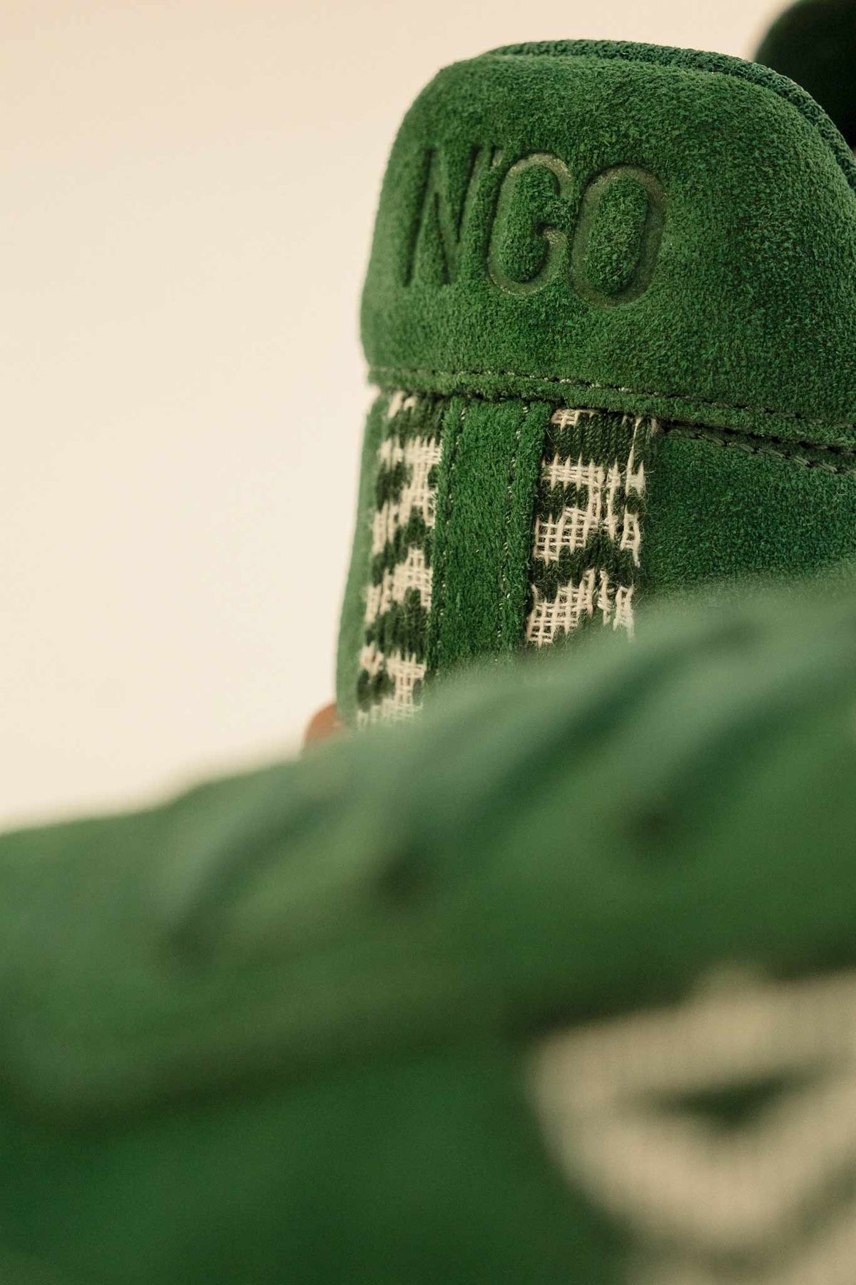 Détail de suède vert et motif tissé main sur des baskets N'GO.